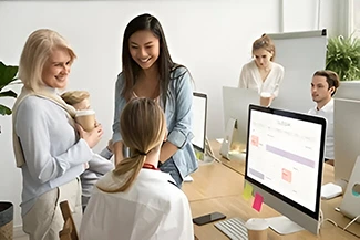 A group of employees engaged in discussion in an office environment, showcasing the impact of women's participation in the economy.